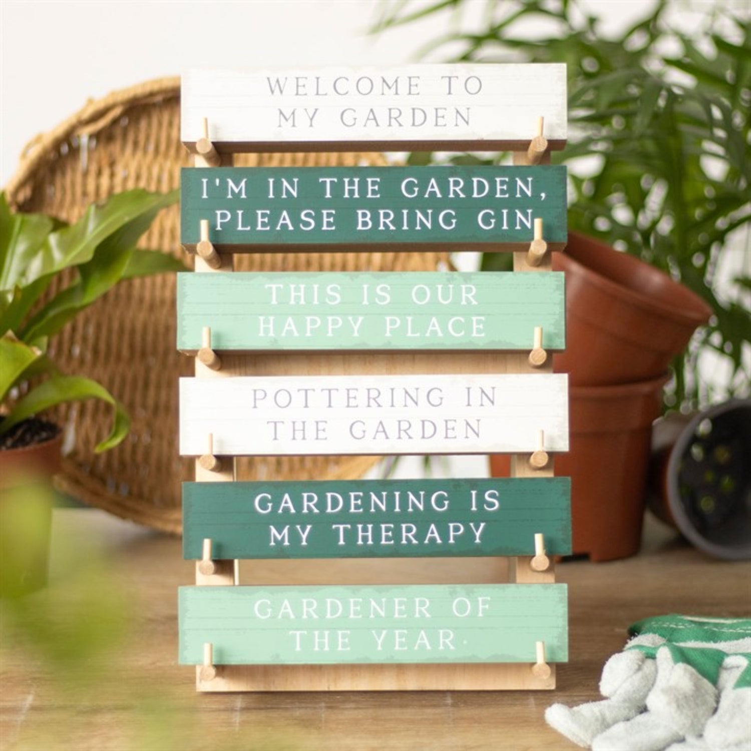Stack of wooden signs with gardening-themed sayings in a garden setting