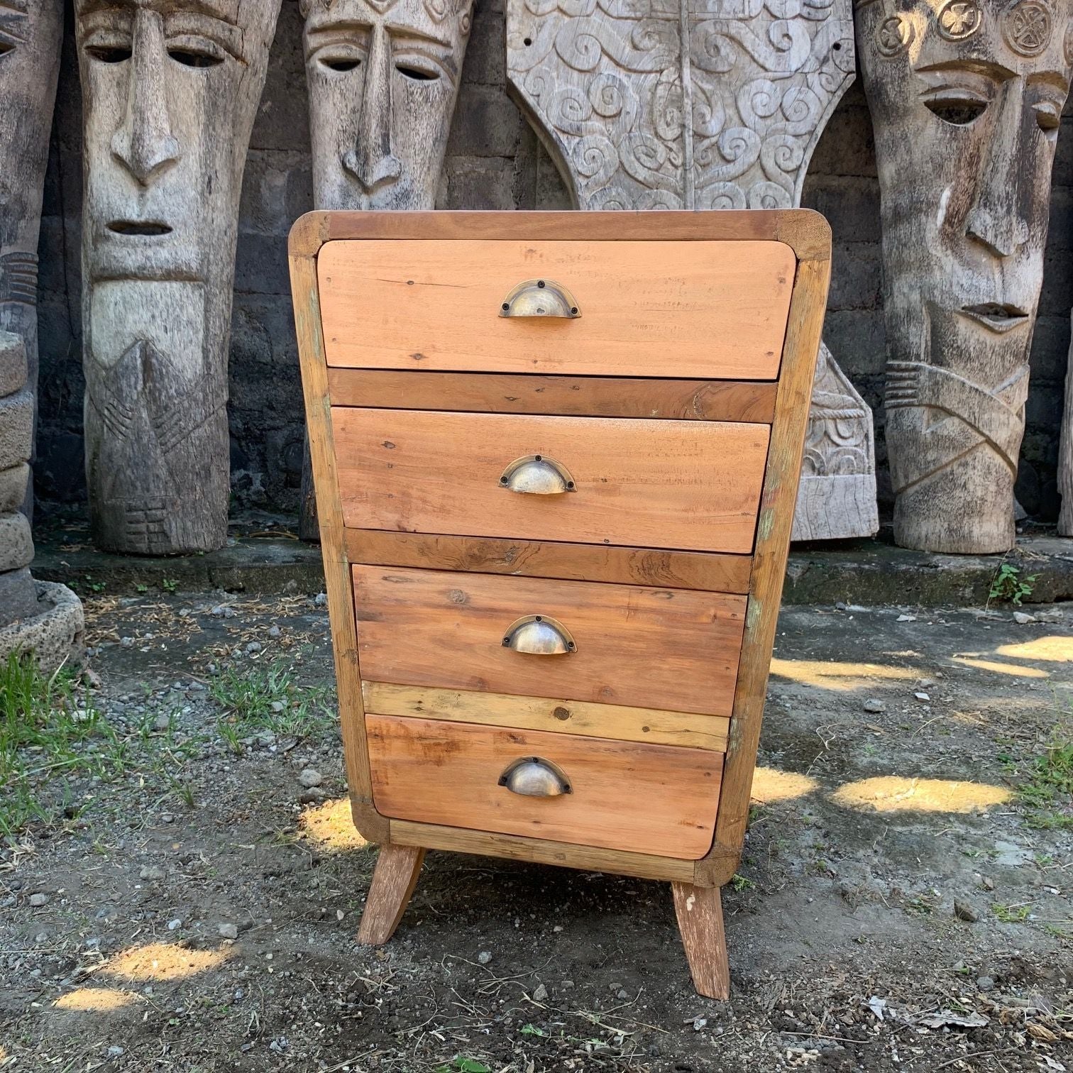 Wooden dresser with four drawers in front of stone sculptures