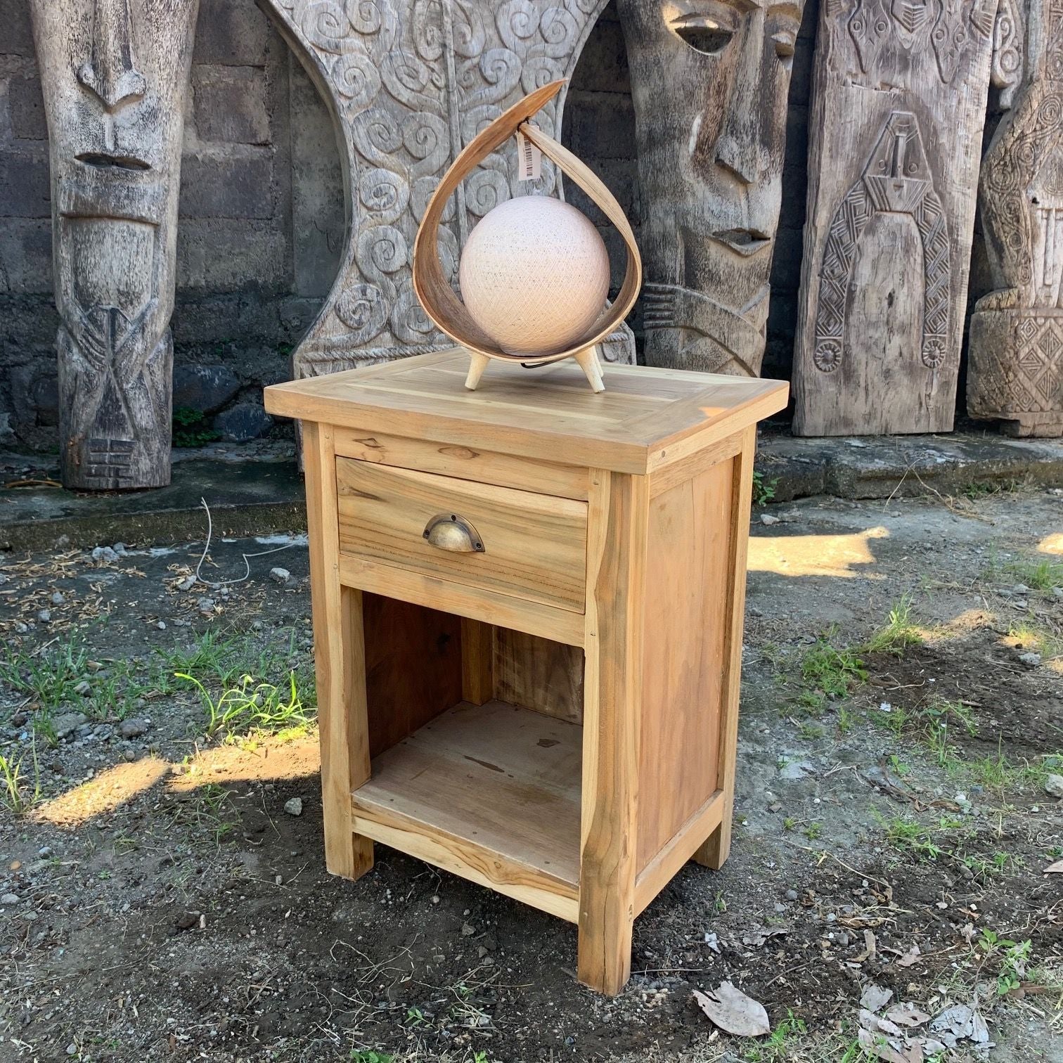 Wooden side table with decorative item in front of stone carvings