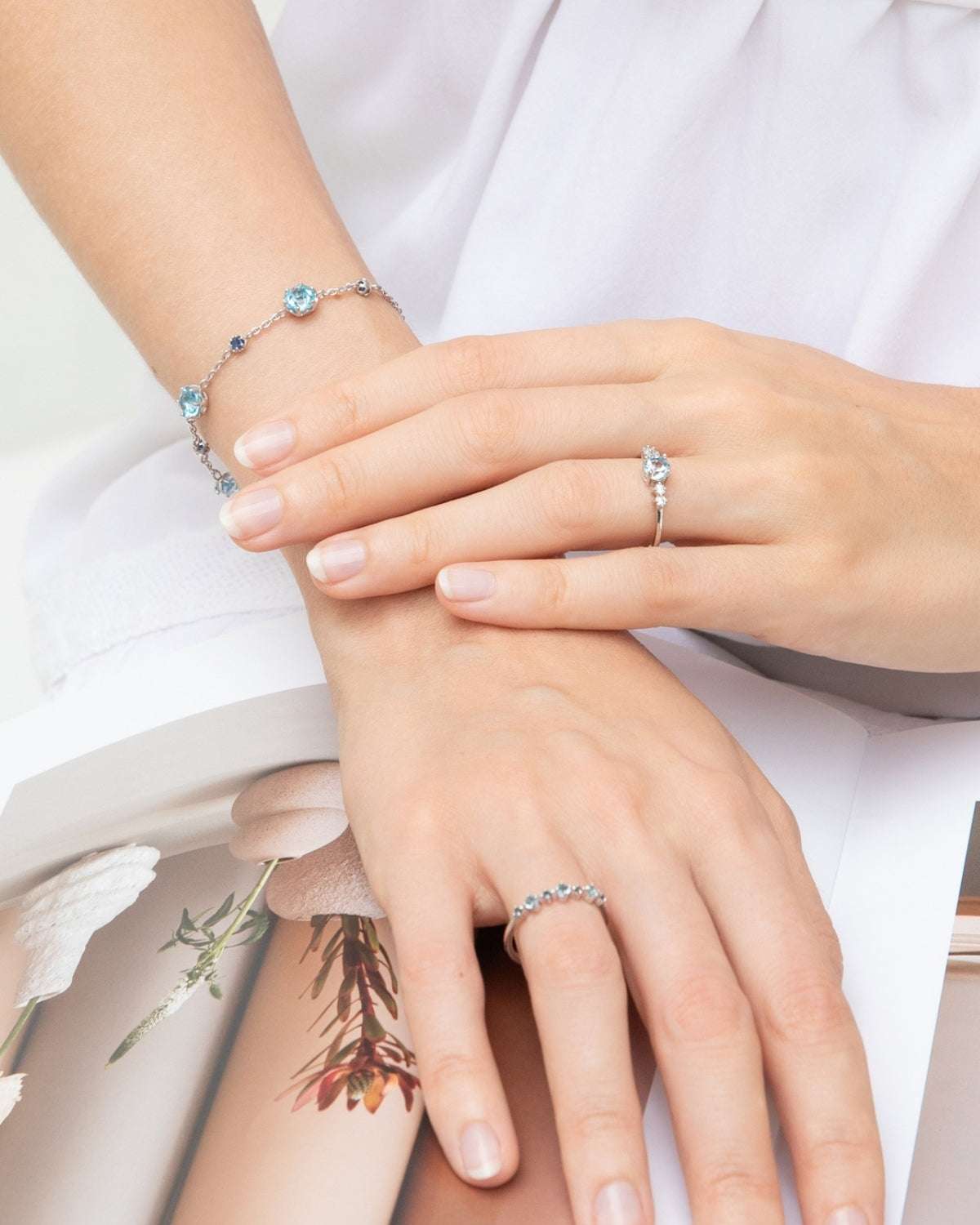 Sterling silver bracelet with blue accents and blue topaz rings on hands