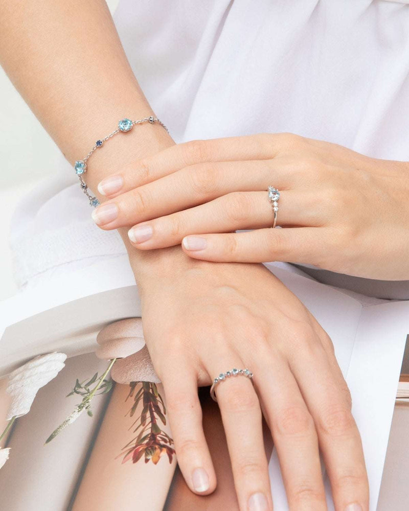 Sterling silver bracelet with blue accents and blue topaz rings on hands