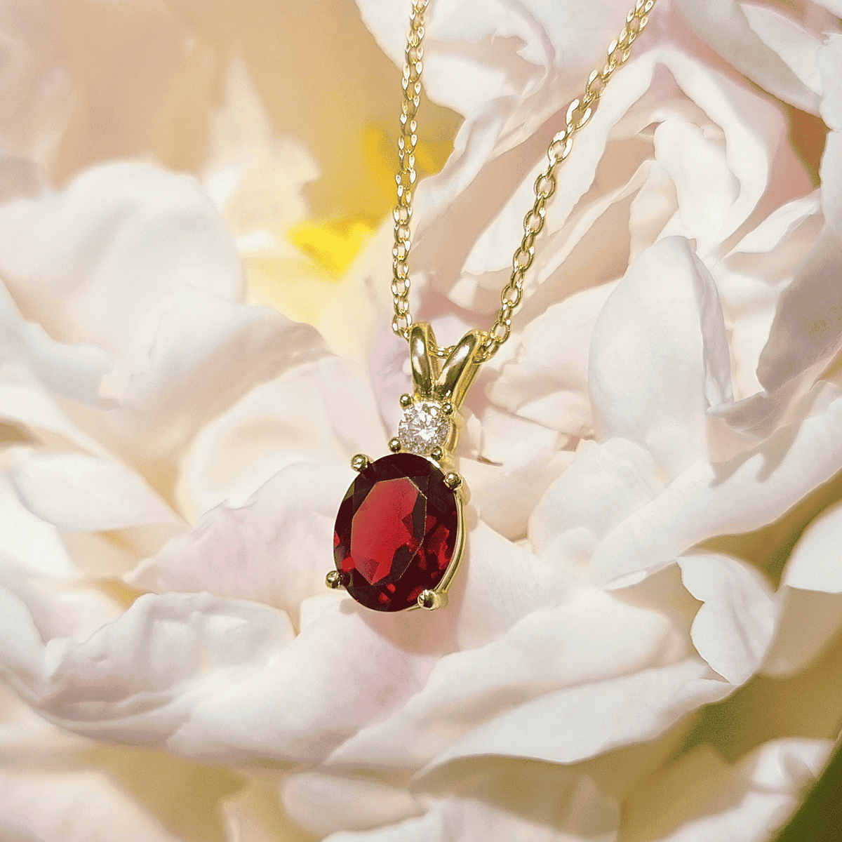 Gold-toned chain necklace with red oval pendant and small diamond accents