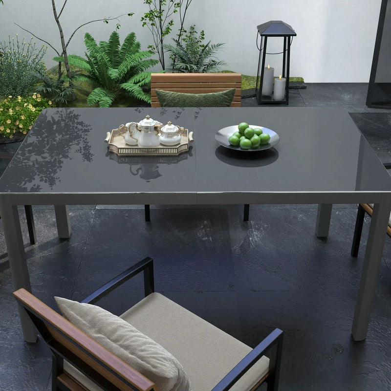 Grey glass-top aluminium table on patio with chairs and small tableware