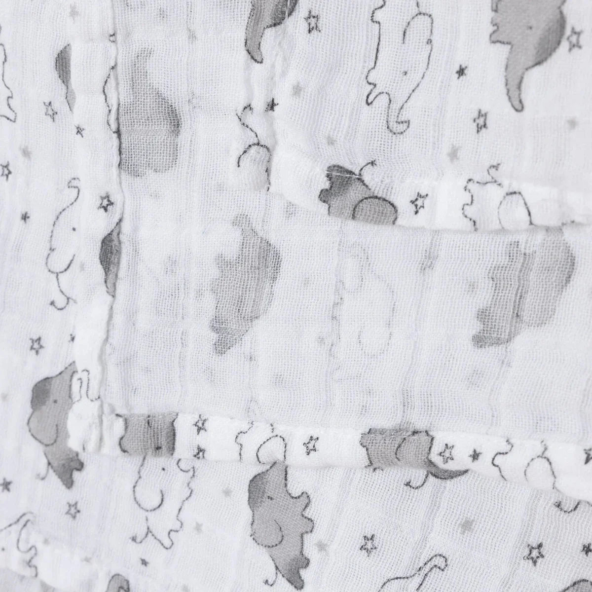 White muslin blanket folds with gray elephant print and subtle star pattern
