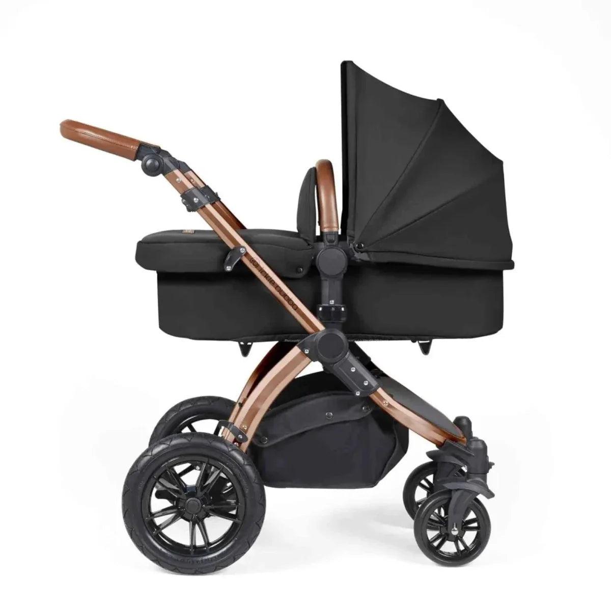 Black stroller with carrycot, bronze handlebar, and tan-accent frame details