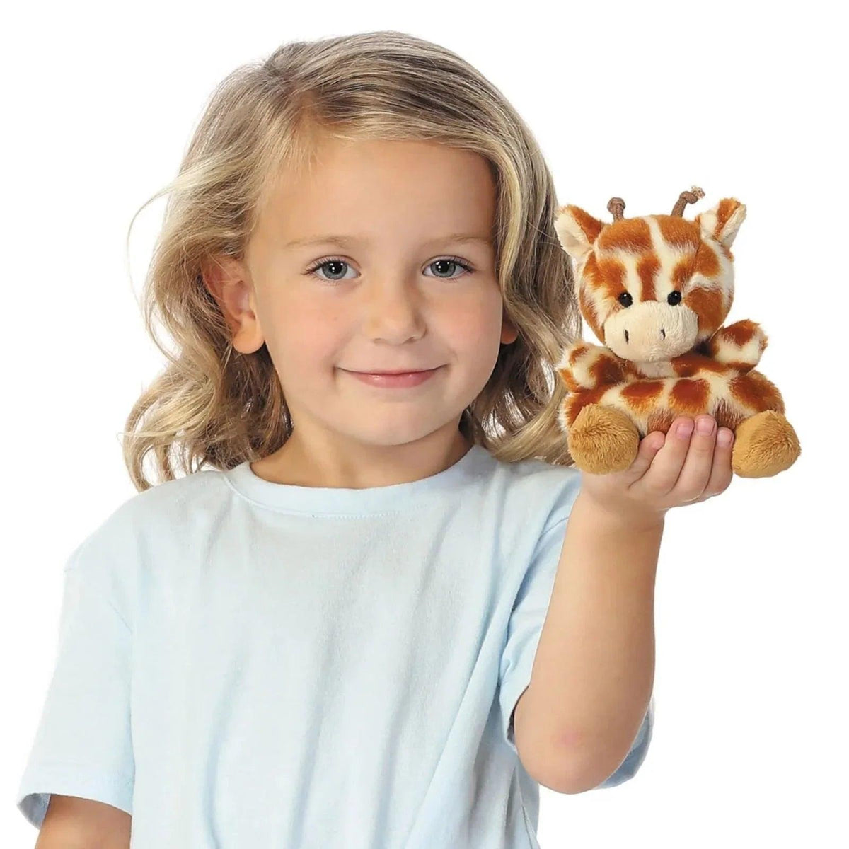 Giraffe plush toy held in a child’s hands, brown-and-cream spots, stitched face