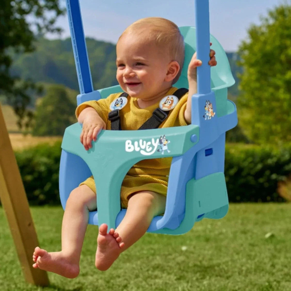 Blue toddler swing seat with character front panel and safety harness, on outdoor frame