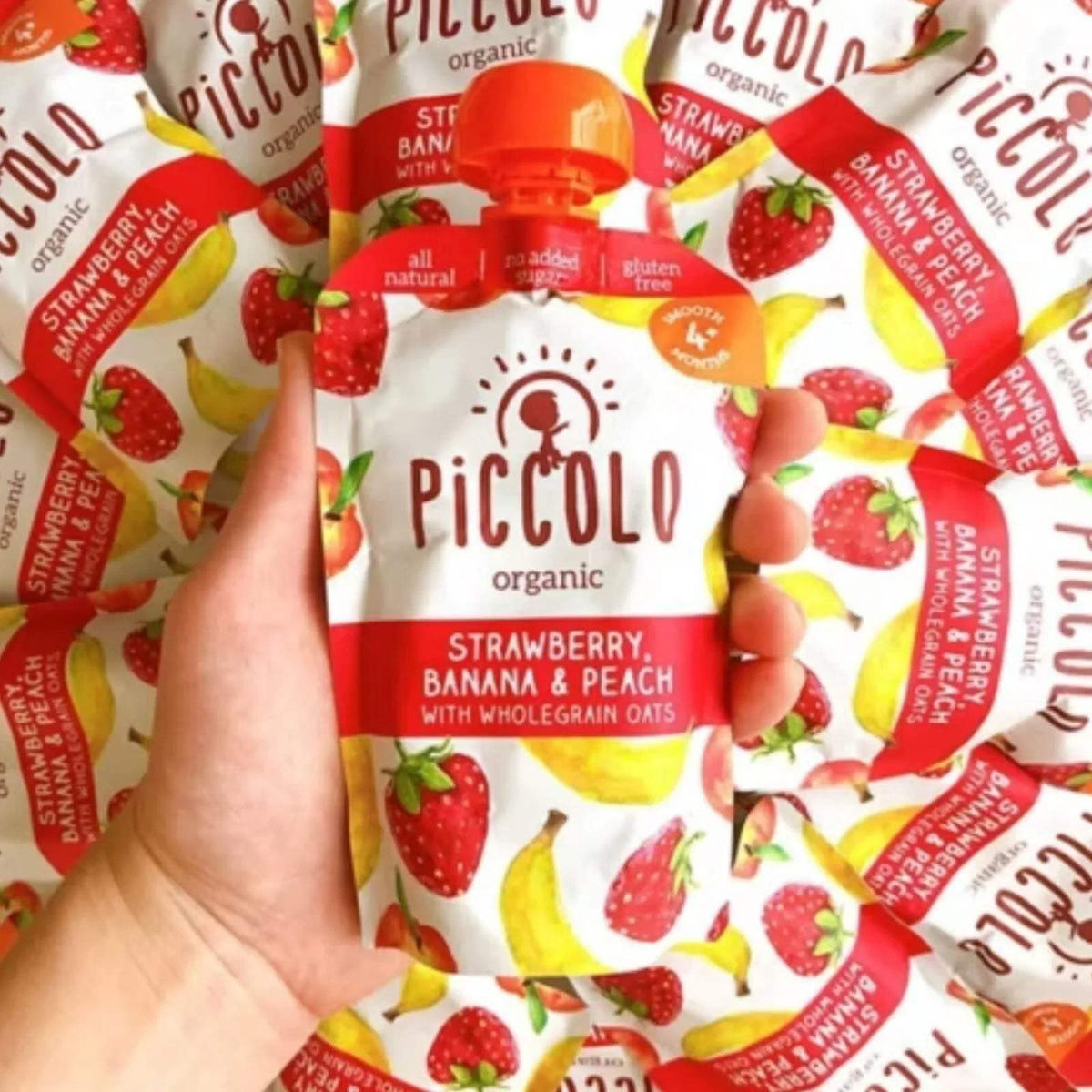Organic strawberry banana and peach baby food pouch held in hand