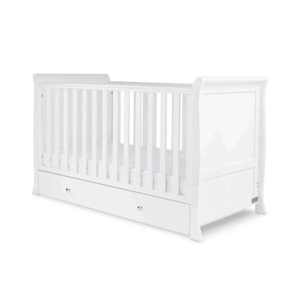 White baby cot with vertical slats, corner posts, and front drawer storage
