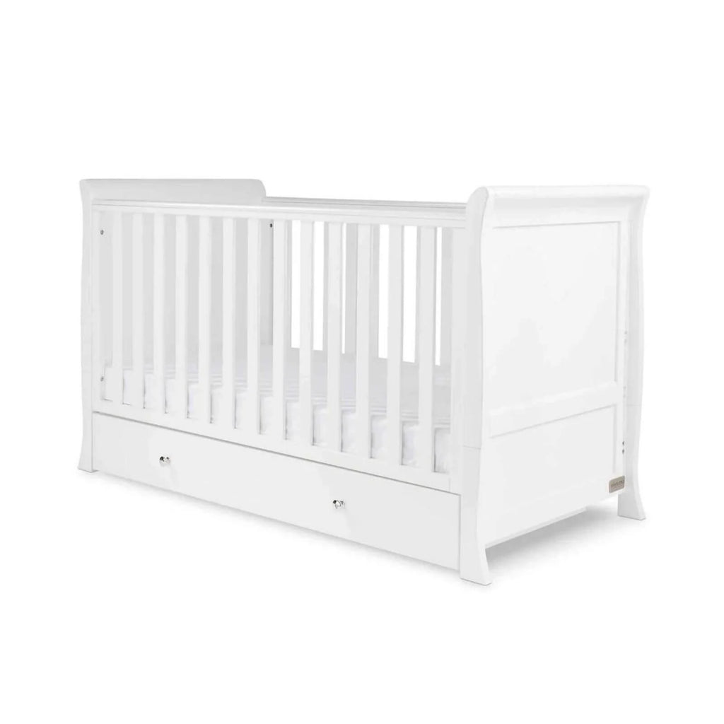 White wooden baby cot with vertical slats and drawer base, front side view