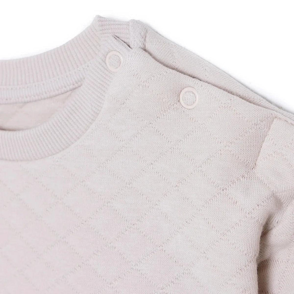 Beige quilted baby sweatshirt with snap buttons on the shoulder