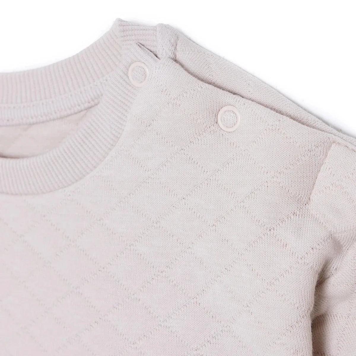 Beige quilted baby sweatshirt with snap buttons on the shoulder