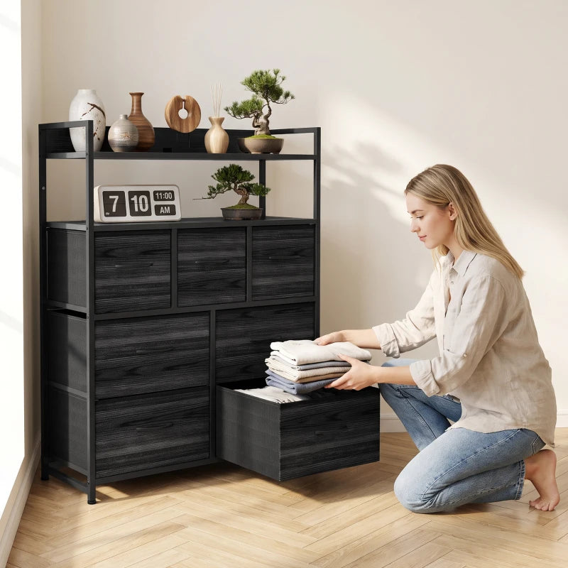 Black wood-effect dresser with open shelves and seven drawers, person loading linens