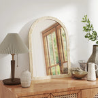 Beige arched wall mirror with textured frame resting on a wooden console