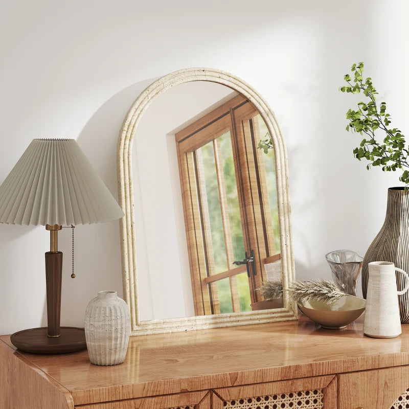 Beige arched wall mirror with textured frame resting on a wooden console