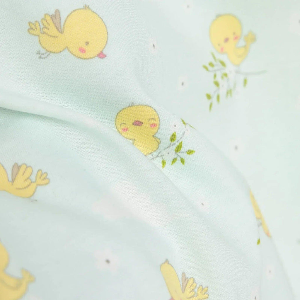 Light blue romper pattern detail close-up with yellow chick graphic and green sprig accents