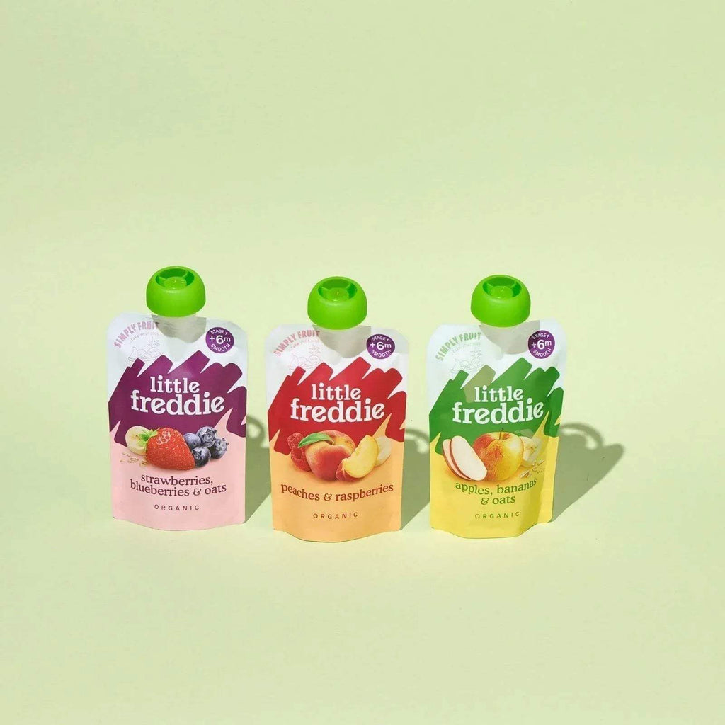 Three Little Freddie baby food pouches with green caps: purple, red-orange, and yellow