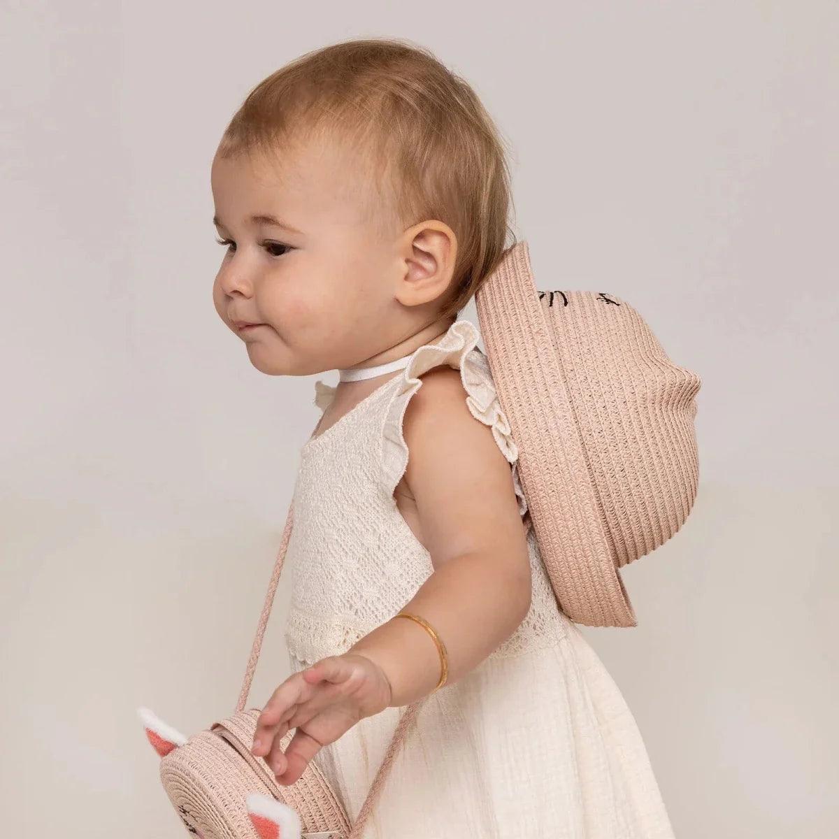 Light pink straw baby hat worn by baby, with wide brim and cat embroidery