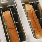 Close-up of black toaster slots with two browned bread slices inside