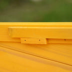 Yellow wooden cat house roof edge detail with visible screws