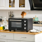 Black mini countertop oven on kitchen counter with glass door and round control knobs
