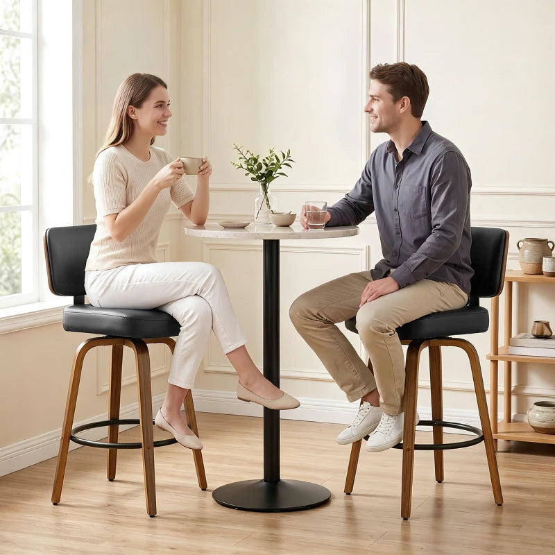 Set of 2 black bar stools with padded curved seats, swivel bases, and round metal footrests