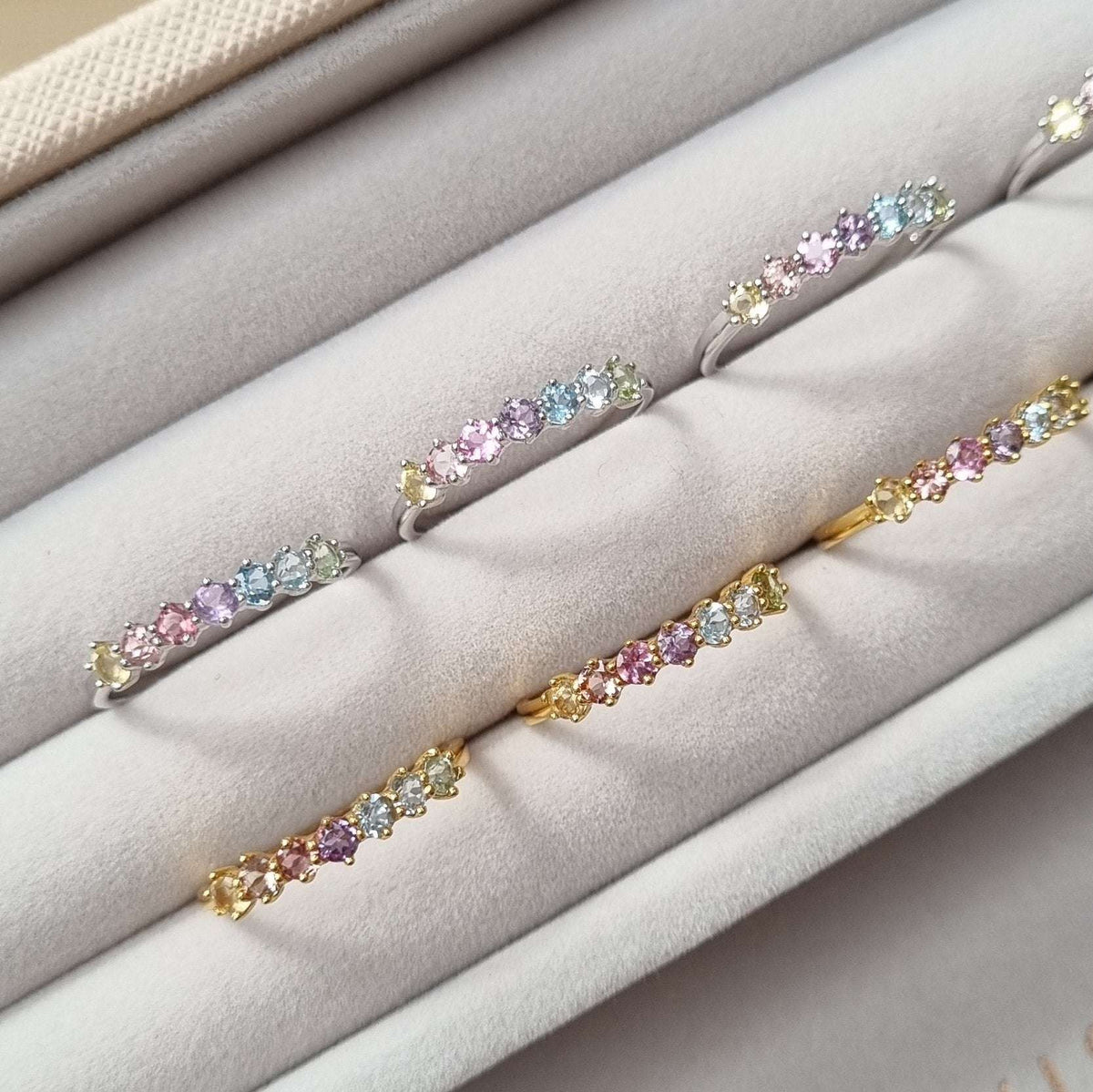 Set of pastel gemstone eternity rings in gold, silver, and rose-gold tones