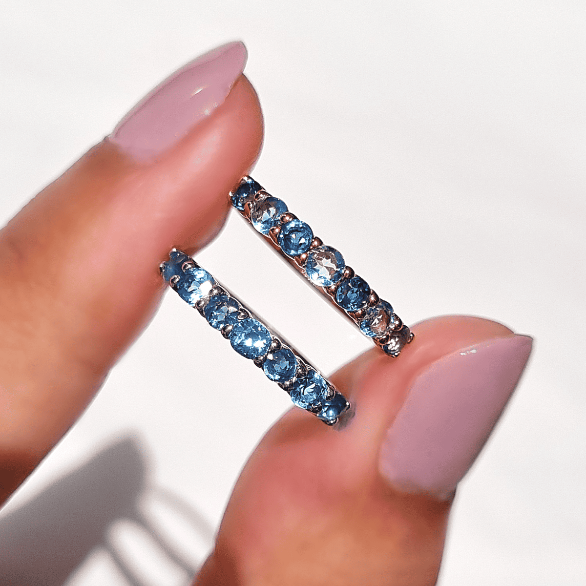 Sterling silver half-eternity ring with oval blue gemstones on fingertips