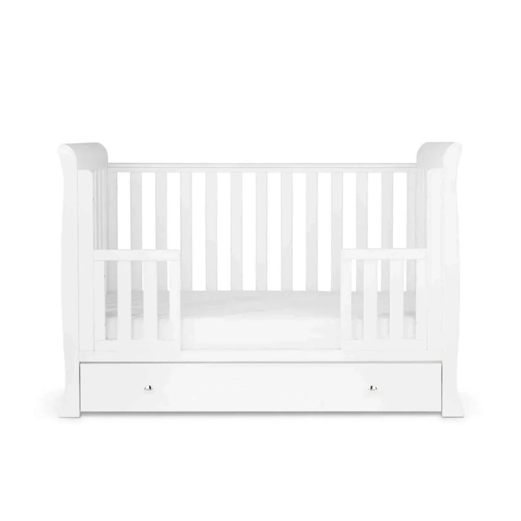 White mini cot bed with front drawer panel and mattress inside the rails