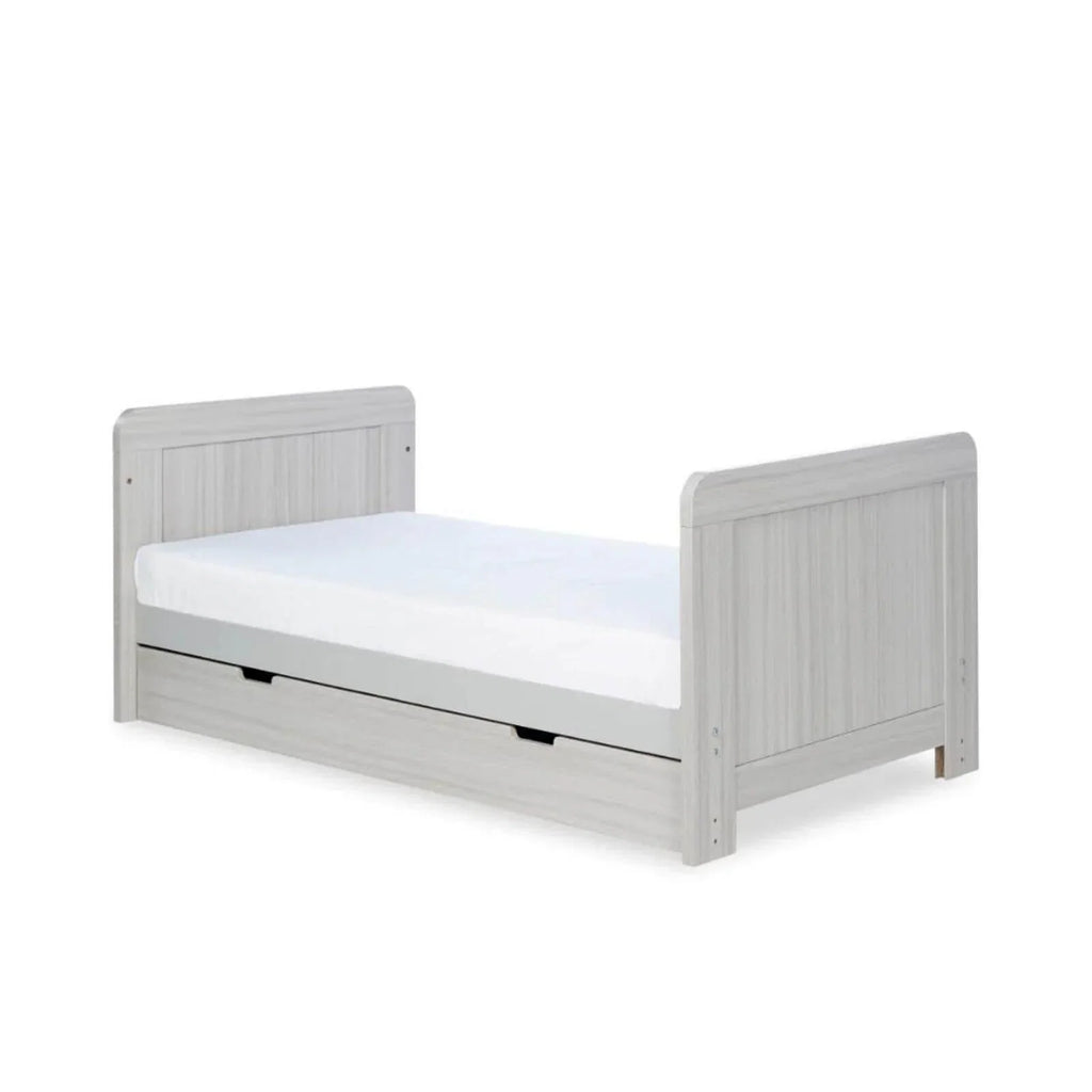 Ash grey cot bed with low side panels, white mattress and drawer front
