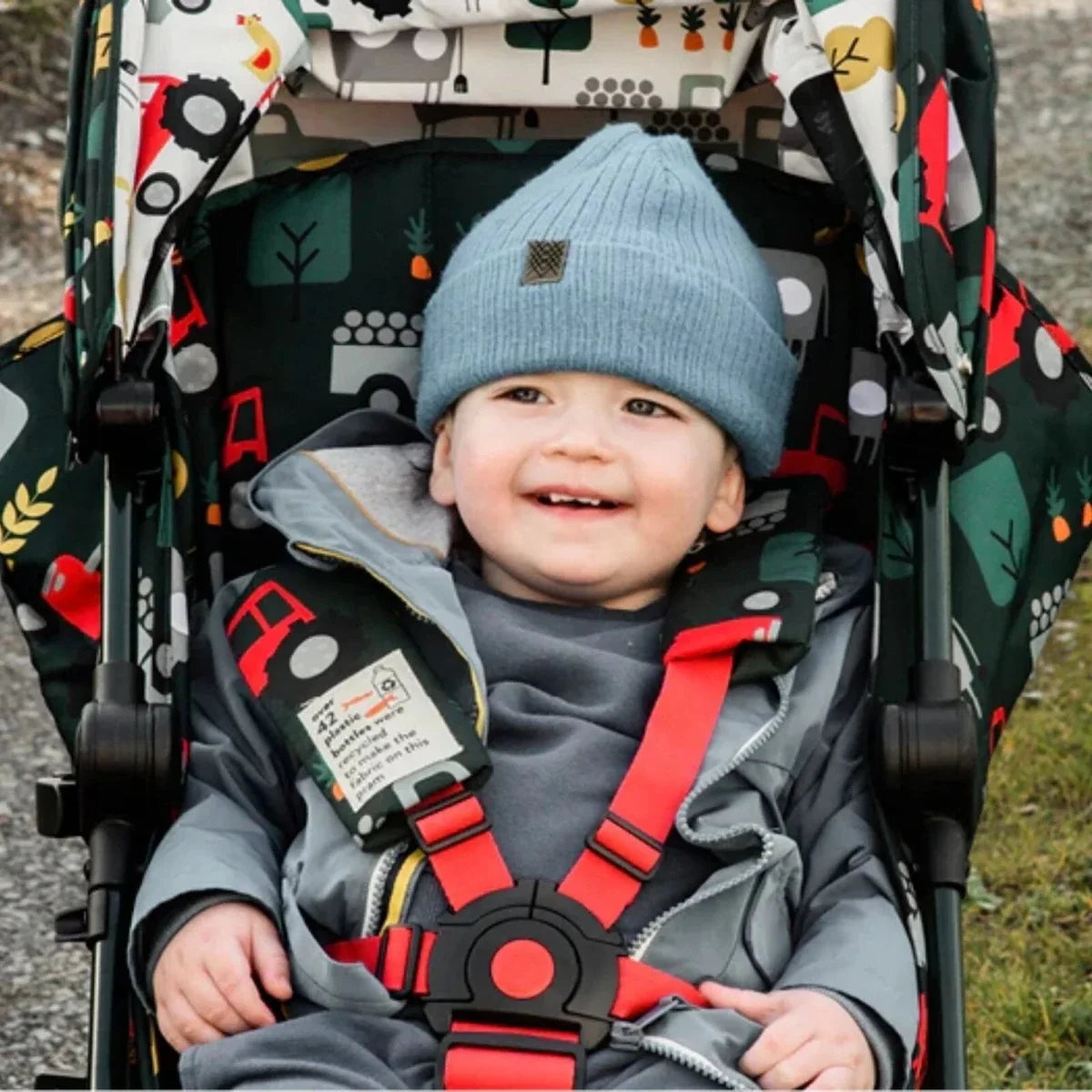 Stroller seat close-up with smiling toddler wearing a blue knit hat