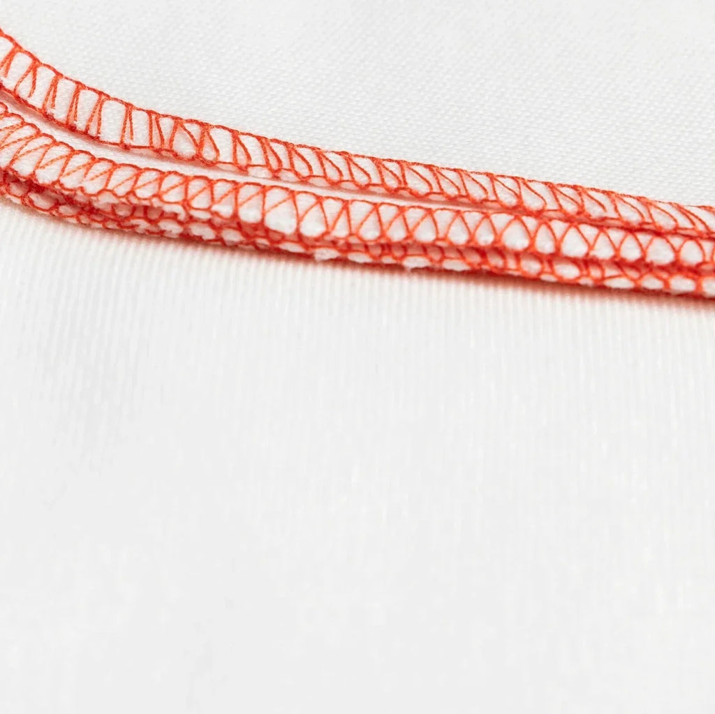 Ecru baby burp cloth edge with red stitched trim and detailed looping seam