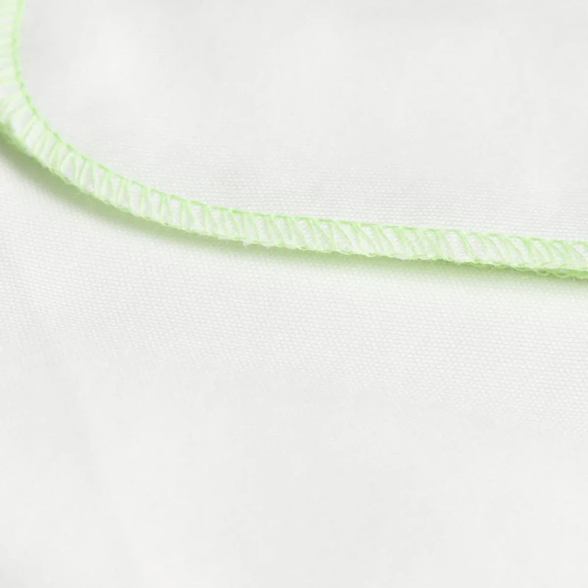 Ecru baby burp cloth edge with light green stitched trim along the border
