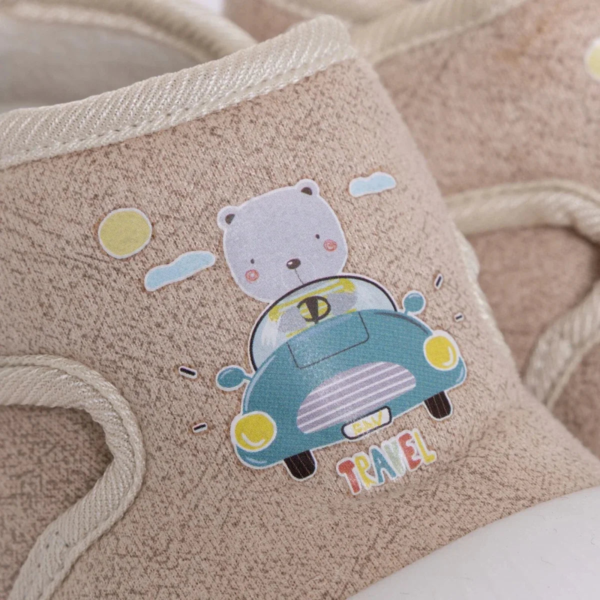 Beige baby shoe with embroidered travel car and bear graphic on side, cushioned collar