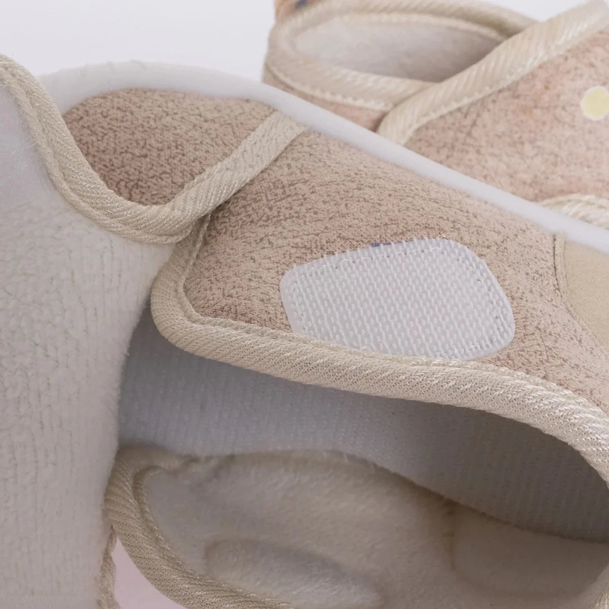 Beige baby shoe close-up of padded opening and collar with white sole edge