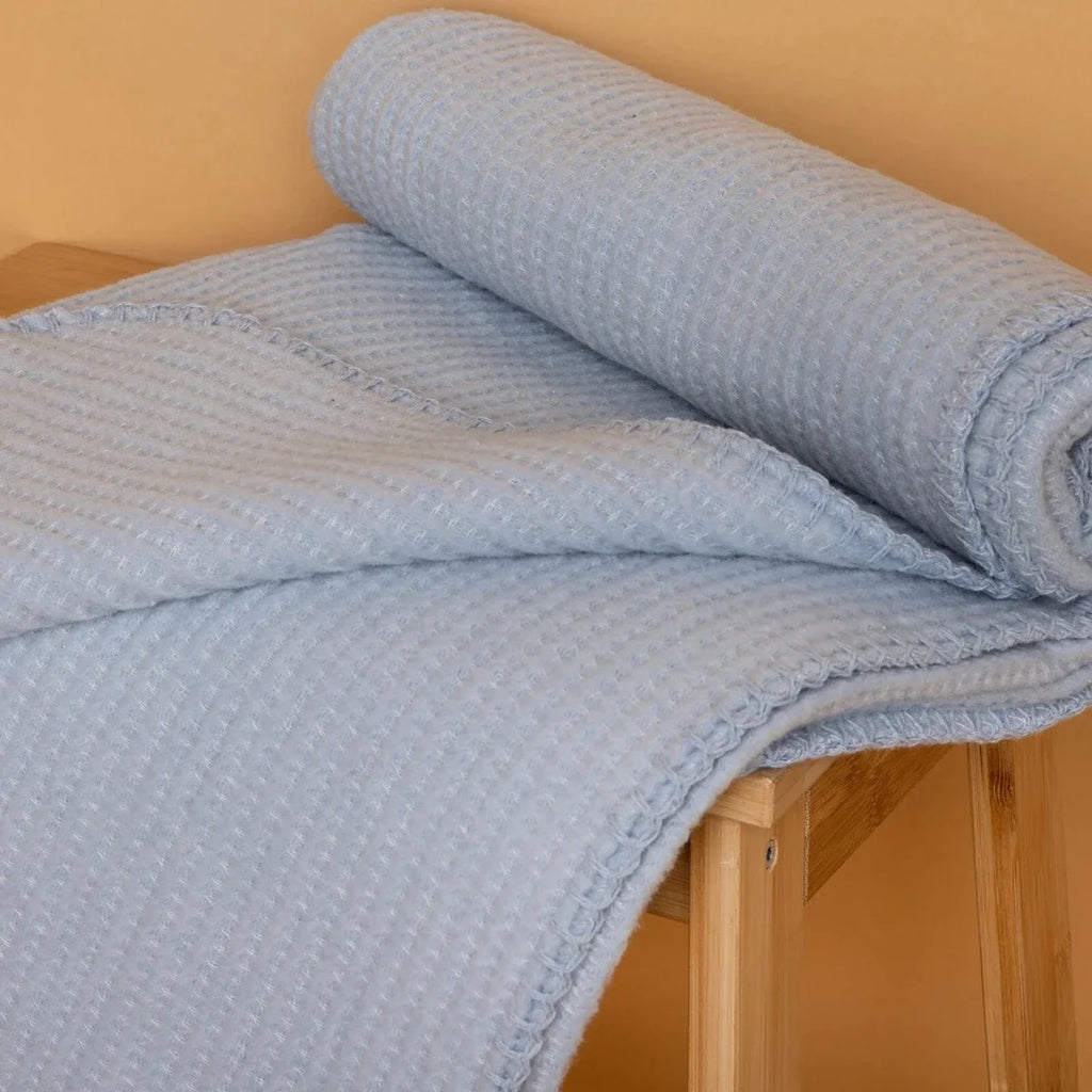Blue waffle-knit baby blanket neatly folded with rolled edge visible