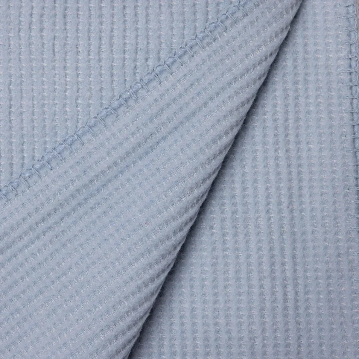 Blue waffle-knit baby blanket close-up of layered folds and seam detail