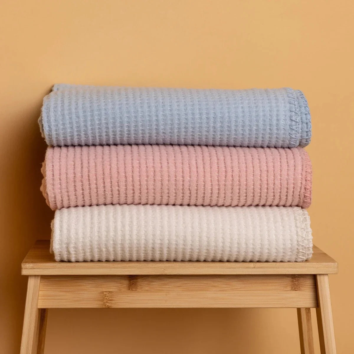 Stack of blue, pink, and white waffle-textured baby blankets on a shelf