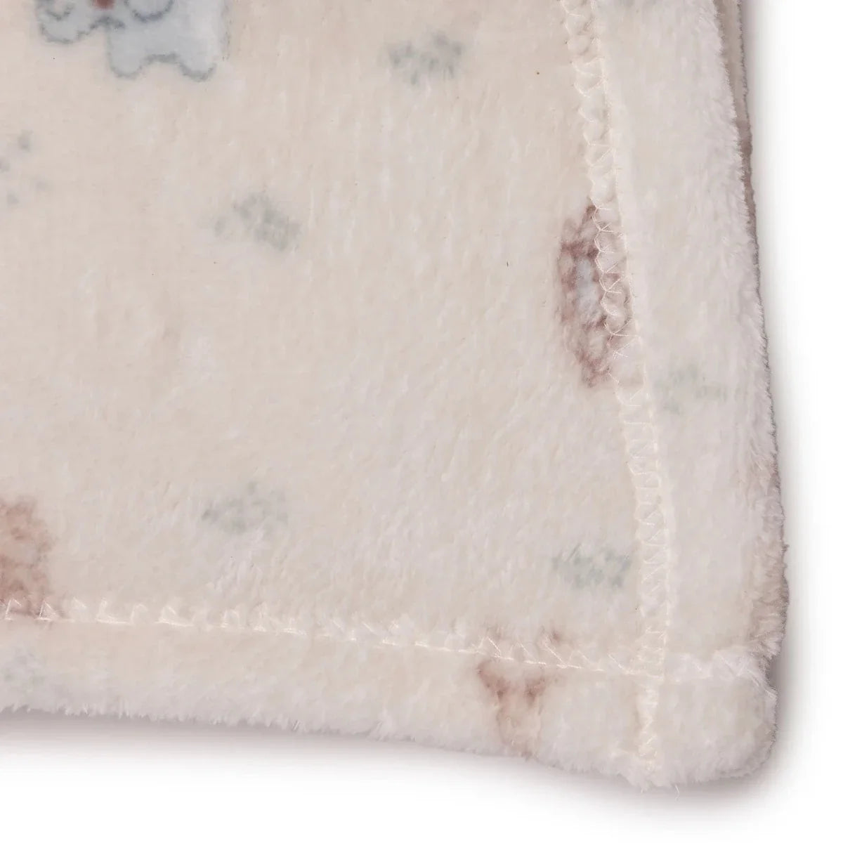 Close-up of cream fleece blanket edge with stitched border and pastel animal print