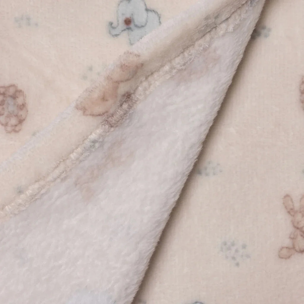 Corner close-up of light cream fleece baby blanket with stitched edge and animal motifs