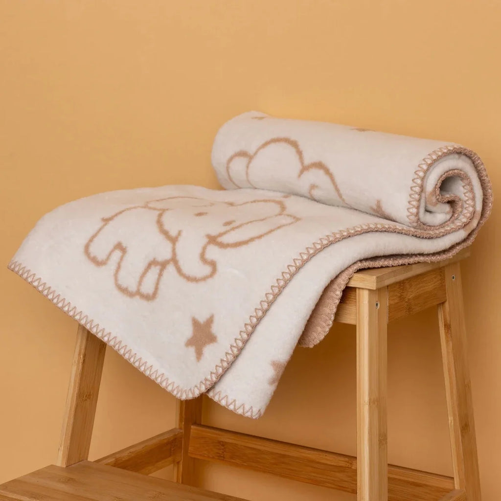 Jacquard knit baby blanket with elephant outline and small stars, folded on a stand