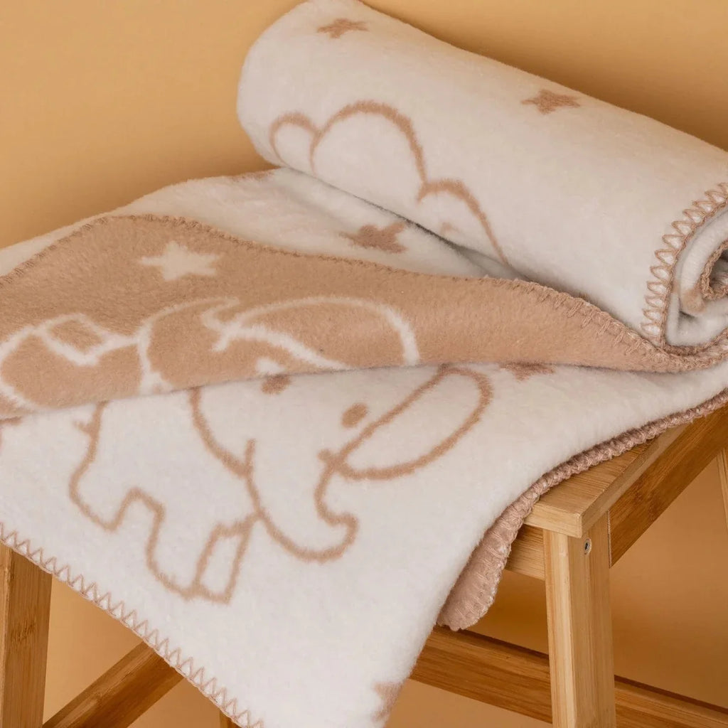 Jacquard knit baby blanket folded, close-up of elephant and star motifs with stitched trim