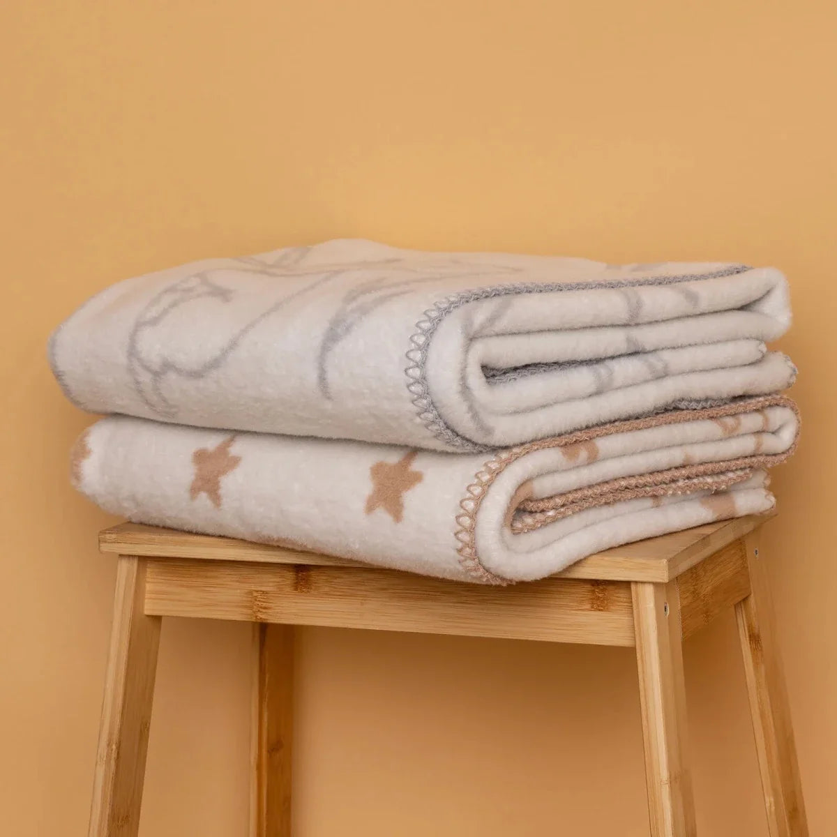 Stack of folded jacquard knit baby blankets with elephant and star motifs