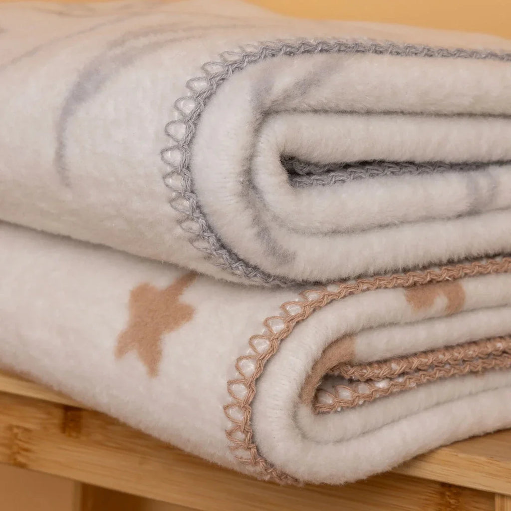 Close-up of folded jacquard knit baby blanket layers with stitched edges and star accents