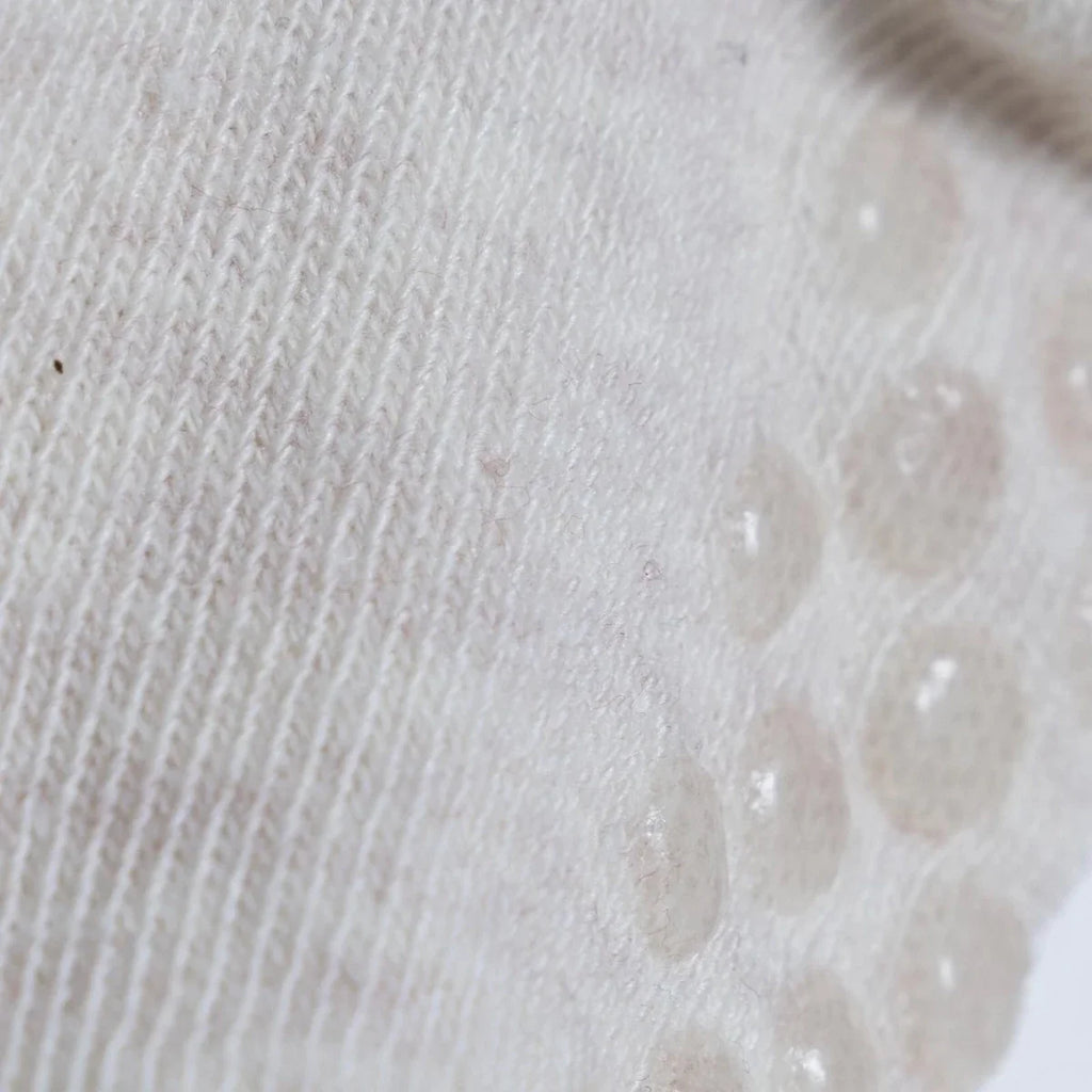 White roll-top baby sock knit with raised dot pattern on the toe area
