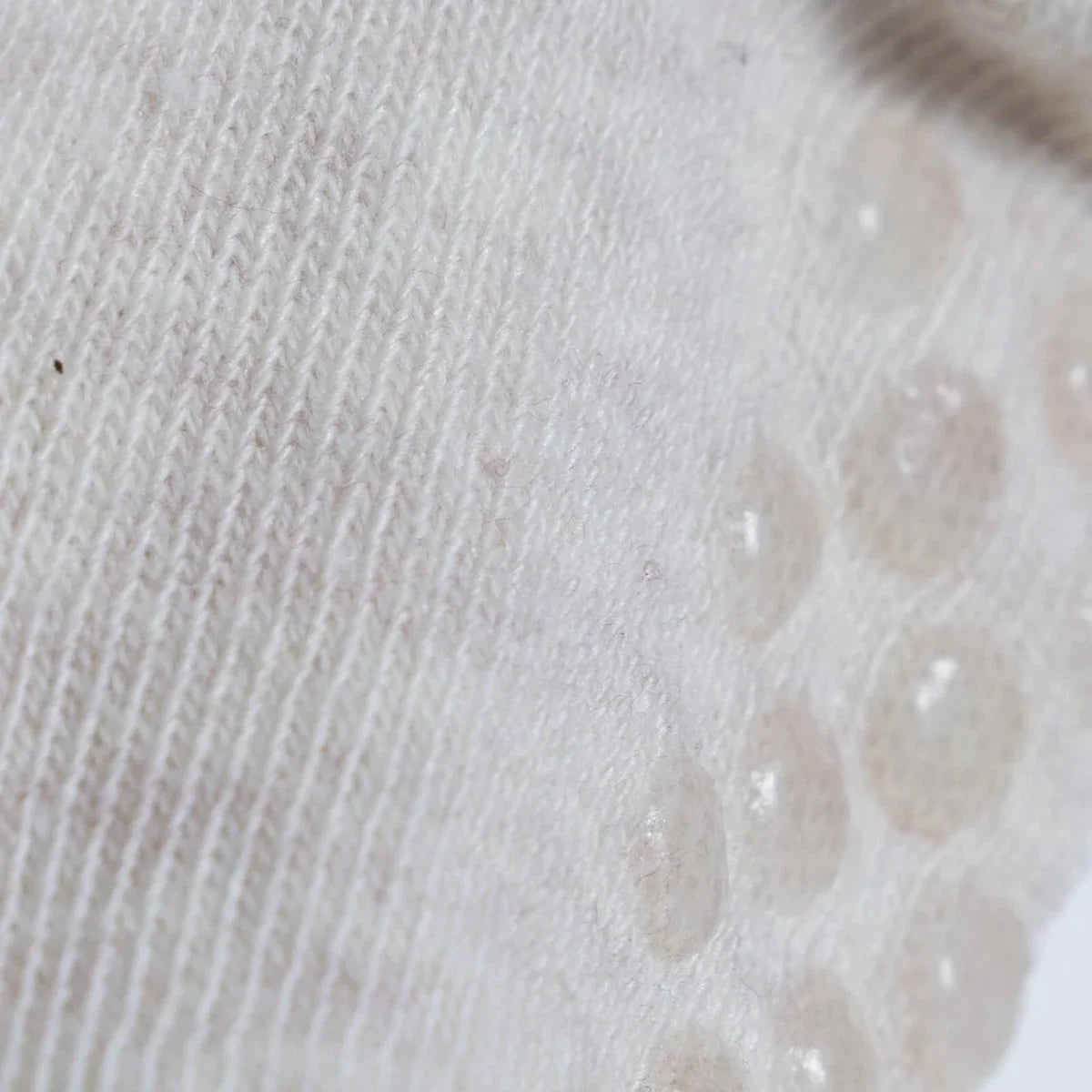 White roll-top baby sock knit with raised dot pattern on the toe area