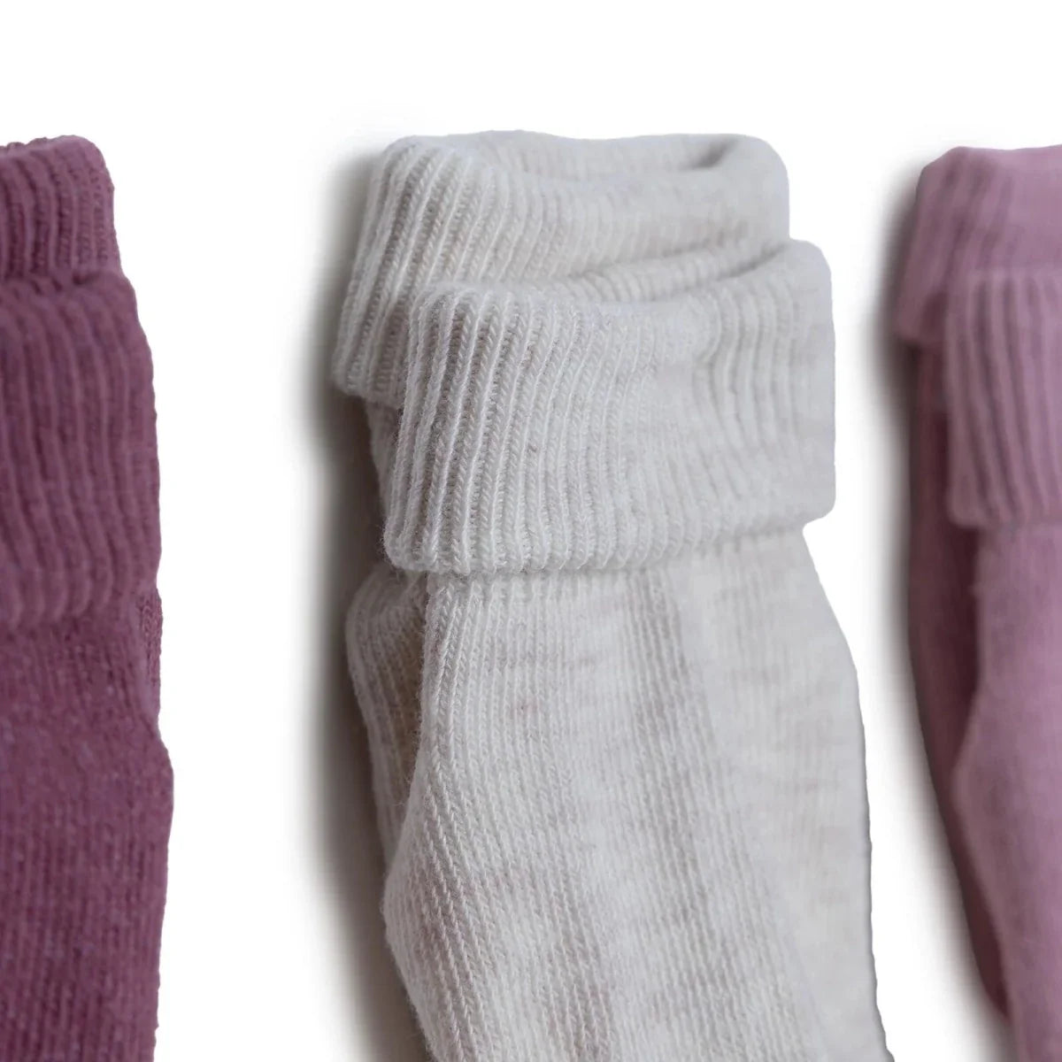 White roll-top baby socks with ribbed cuffs stacked side by side