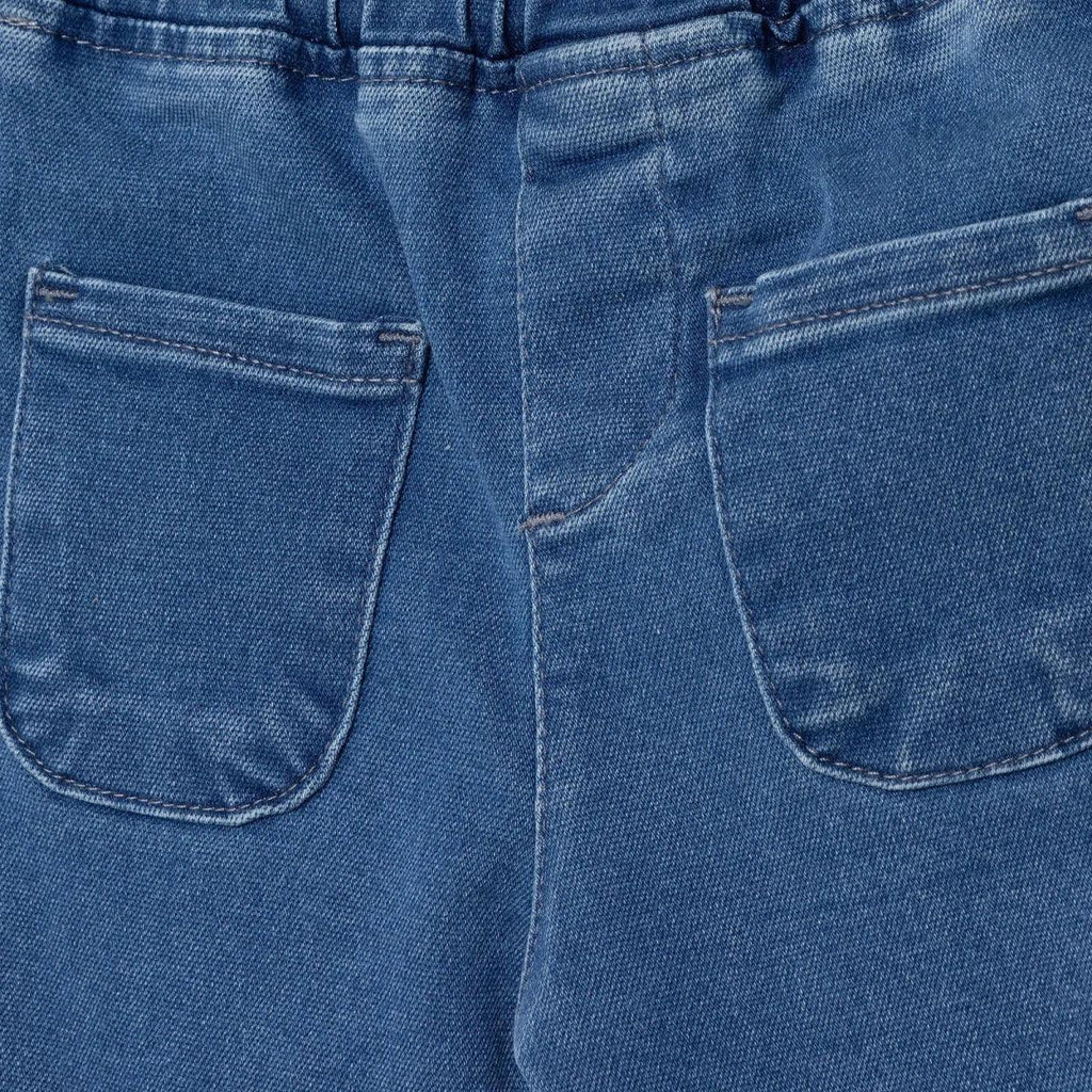 Indigo denim trousers front close-up: two patch pockets and center seam