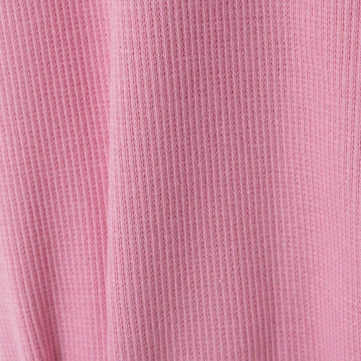 Pink ribbed fabric texture close-up on baby sleepsuit