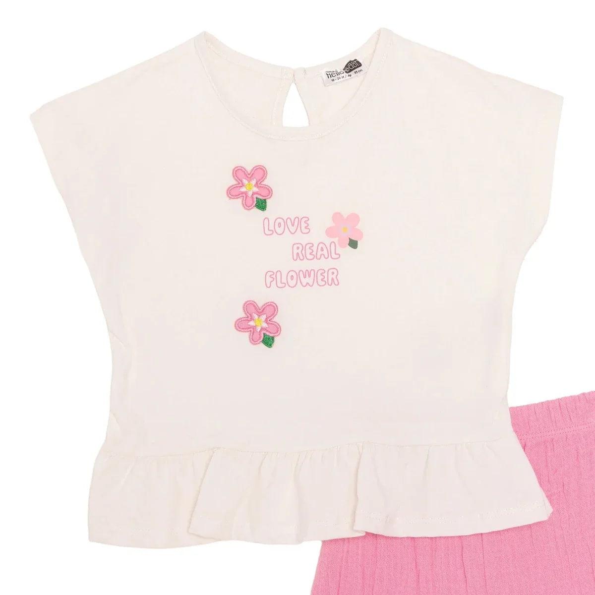 Ecru baby t-shirt with Love Real Flower graphic and pink ruffle shorts.